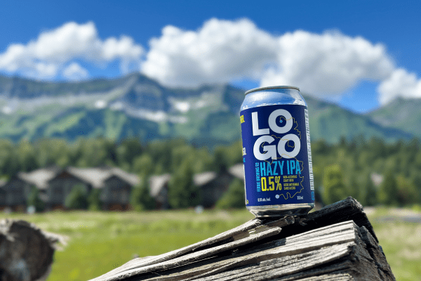 A can of LOGO Hazy IPA on a log with mountains in the background