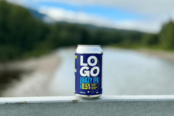 A can of LOGO Hazy IPA on a railing looking over a river